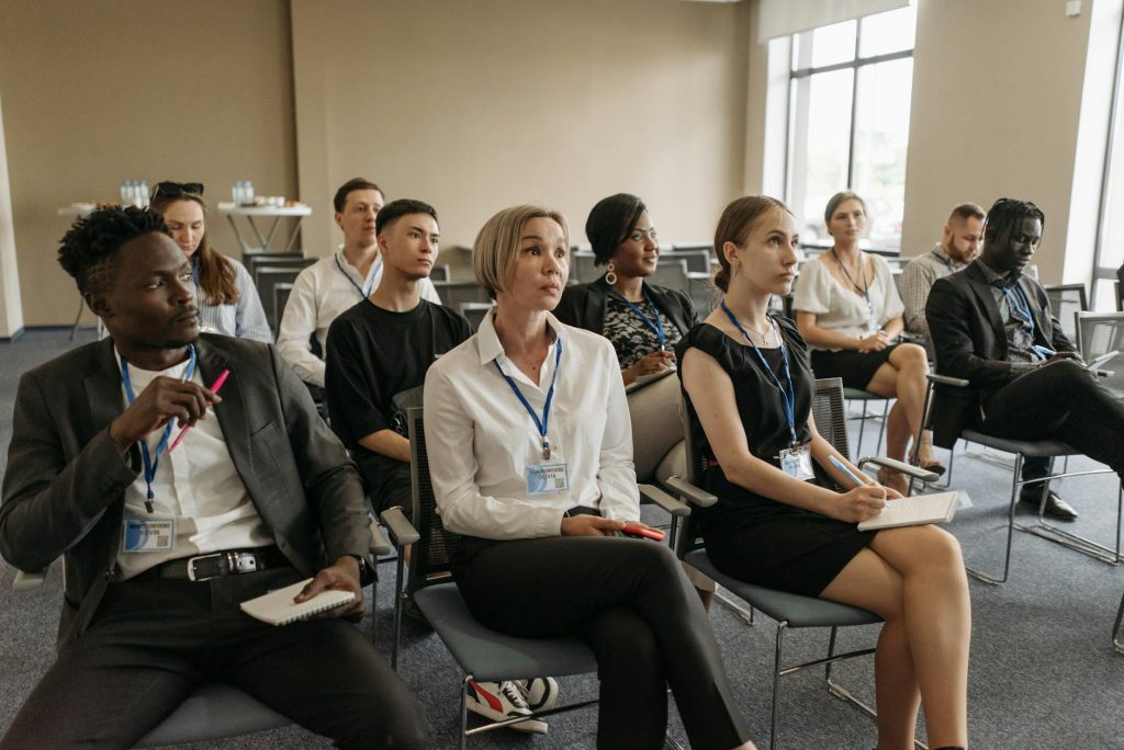 A diverse group of professionals attending an indoor meeting, taking notes and listening attentively.