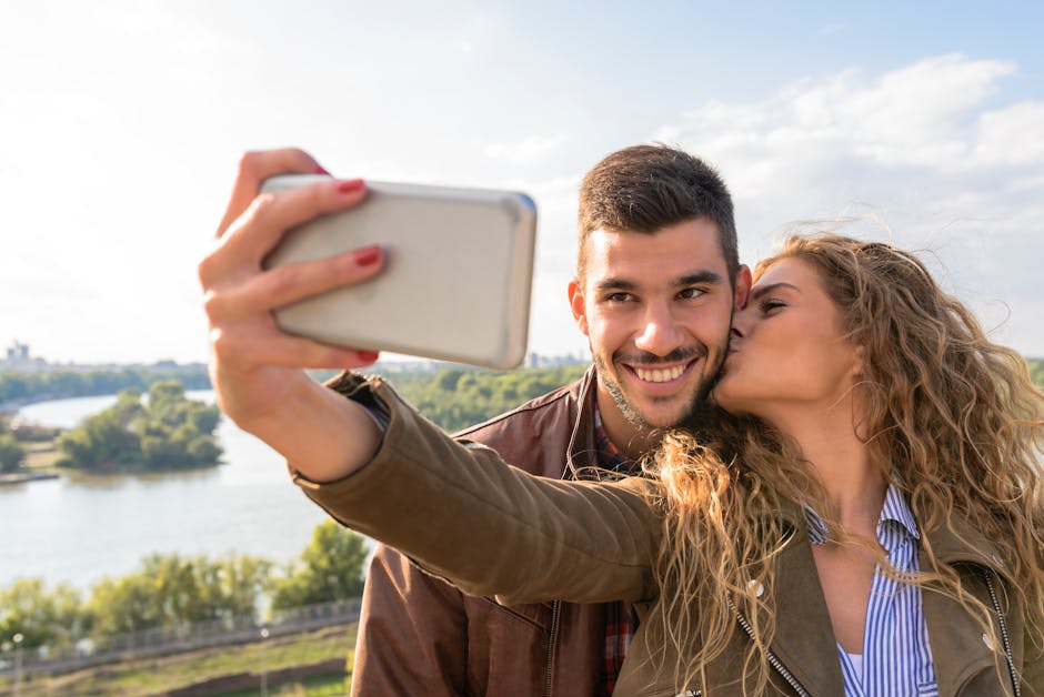 A happy couple taking a romantic selfie by the scenic riverside on a sunny day.